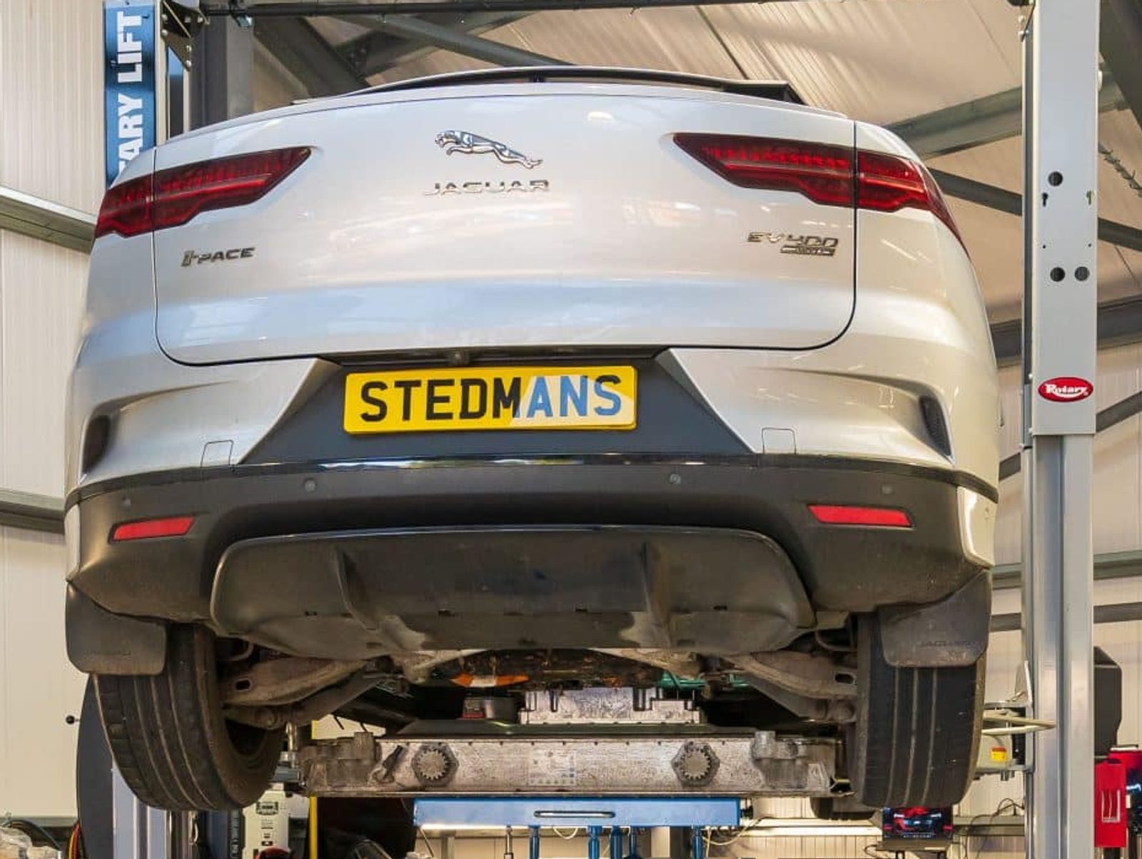 A Jaguar I-Pace EV400 raised on the ramp with its battery pack exposed during EV servicing at Stedmans Garage in Worthing