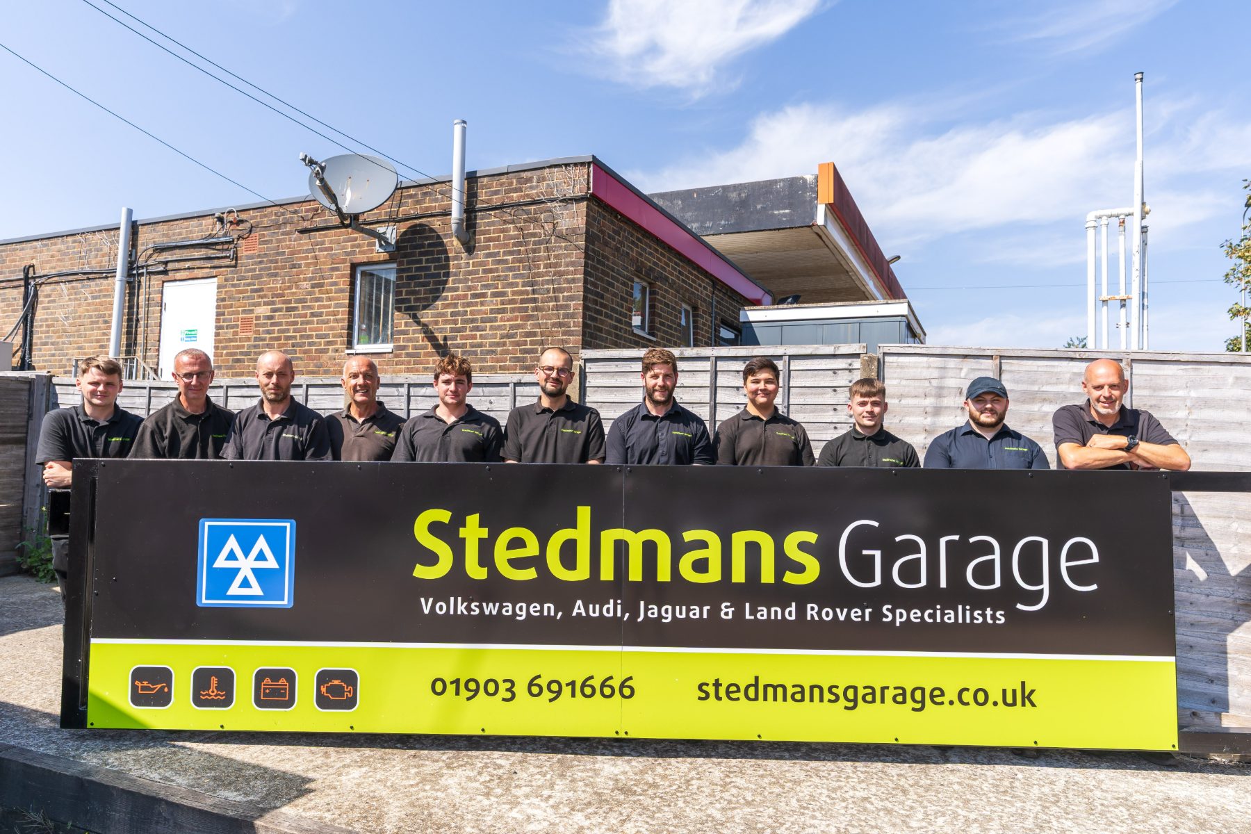 The Stedmans Garage team in front of the branded workshop sign